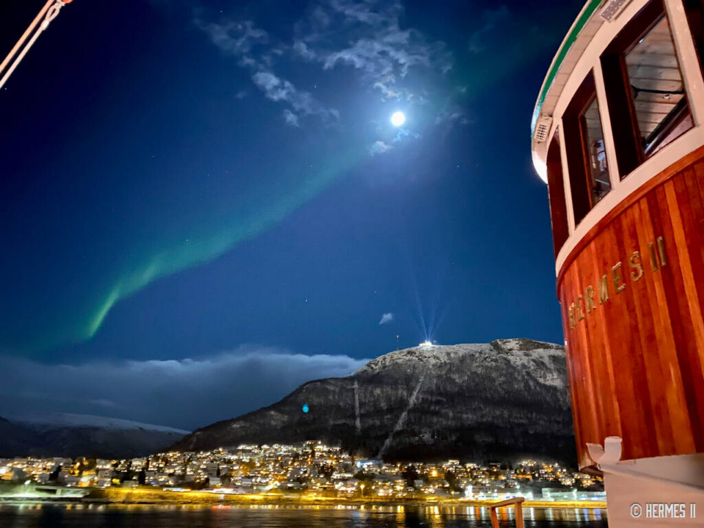 Nordlyset speiler seg i fjorden utenfor Tromsø