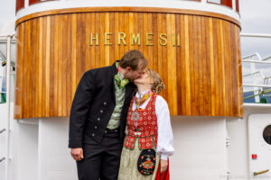 Brudeparet Kristin og Bjørn kysser ved navneskiltet på Hermes II i Tromsø