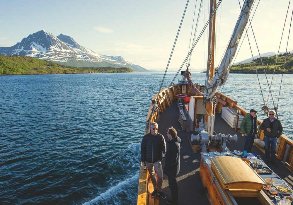 båt på havet med folk om bord og fjell i bakgrunnen. foto.